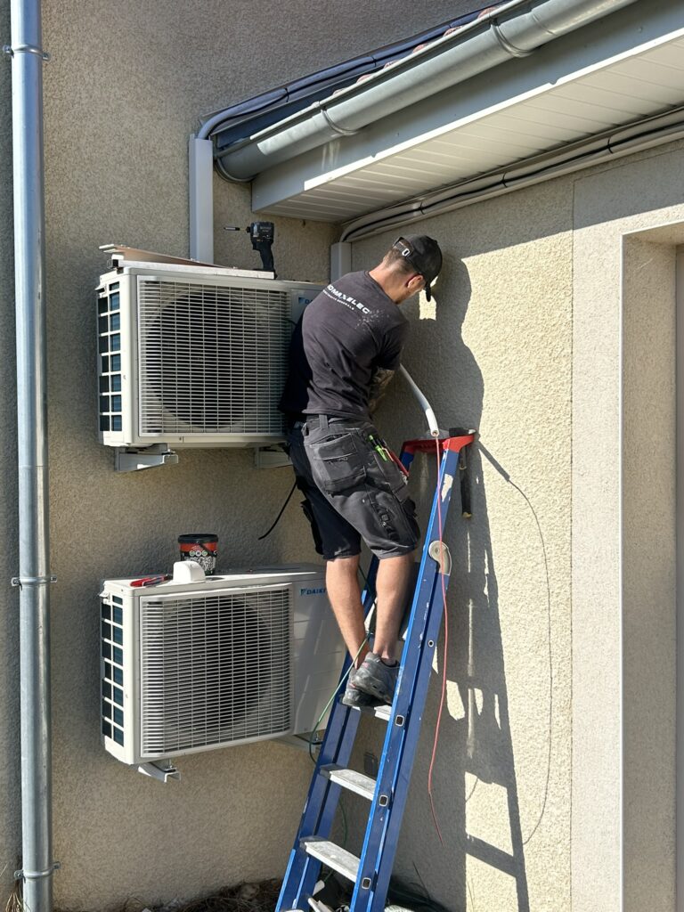 Technicien PROMAXELEC posant deux unités extérieures en façade
